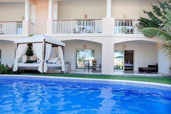 Ein Swimmingpool vor dem Hotel Majestic Elegance Punta Cana mit einem betten bereich und terrasse.