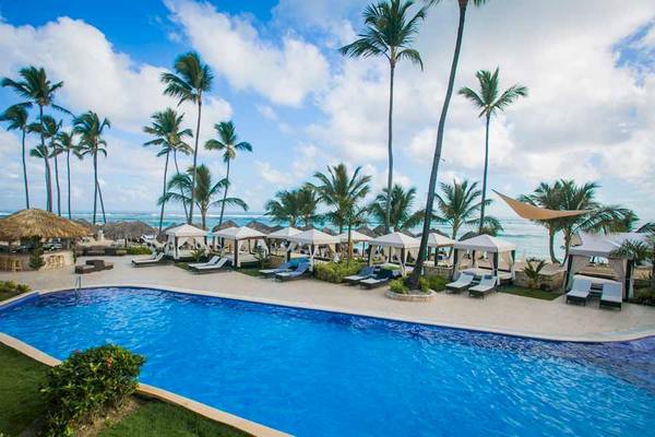 Außenpoolbereich des Majestic Elegance Punta Cana Hotels mit Sonnenliegen und weißen Zelten.