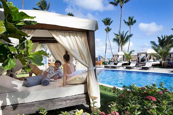 Paar im Pool-Lounge-Bett im Majestic Elegance Punta Cana Hotel.