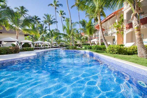 Ein großer Swimmingpool im Freien im Majestic Elegance Punta Cana Hotel, umgeben von Palmen und Cabanas.