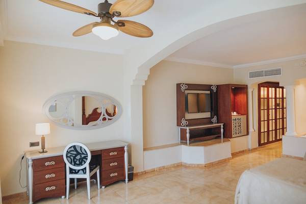 Suite-Innenraum im Majestic Elegance Punta Cana mit Schreibtisch, Stuhl und Fernseher.