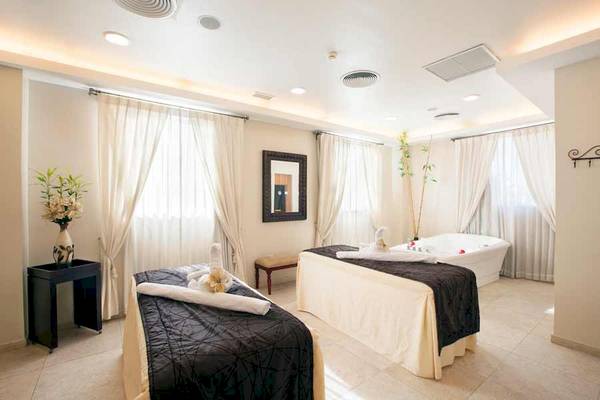 Spa-Bereich im Majestic Elegance Hotel mit zwei Massagebetten und einer Badewanne.