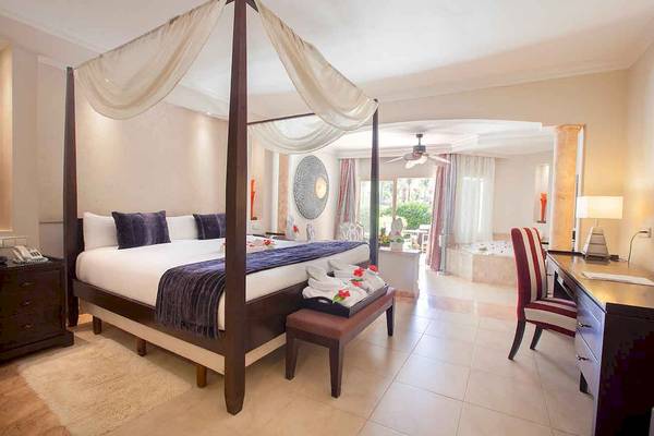 Schlafzimmer im Majestic Elegance Punta Cana mit Baldachinbett, Badezimmer und Whirlpool.