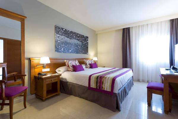 Hotelzimmer im Grand Palladium Palace Ibiza Resort & Spa mit Doppelbett, Nachttischen und Telefon.