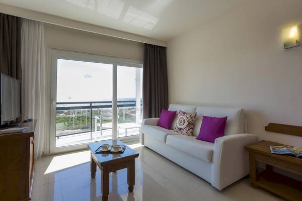 Wohnzimmer des Grand Palladium Palace Ibiza Resort & Spa mit weißem Sofa, Tisch und Meerblick.