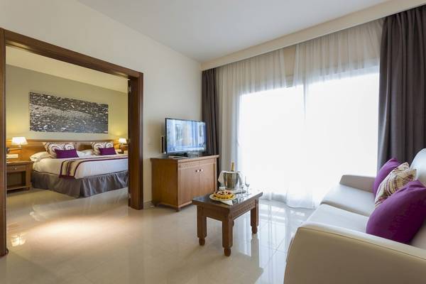 Suite-Zimmer im Grand Palladium Palace Ibiza Resort & Spa mit Wohnzimmer und Schlafzimmerbereich.