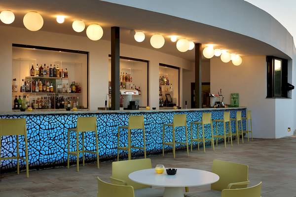 Bar im Grand Palladium Palace Ibiza Resort & Spa mit blau beleuchteten Stühlen und einer Theke mit Flaschen