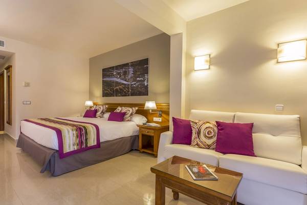 Hotelzimmer des Grand Palladium Palace Ibiza Resort & Spa mit Bett, Sofa und Nachttisch.