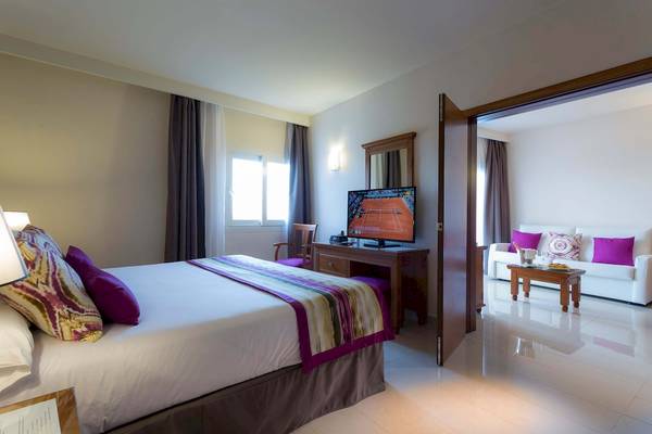 Zimmer im Grand Palladium Palace Ibiza Resort & Spa mit Doppelbett, Fernseher und offenem Wohnzimmer