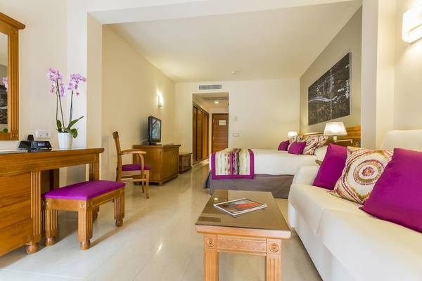 Innenansicht der Suite im Grand Palladium Palace Ibiza Resort & Spa mit Bett, Sofa und Fernseher.