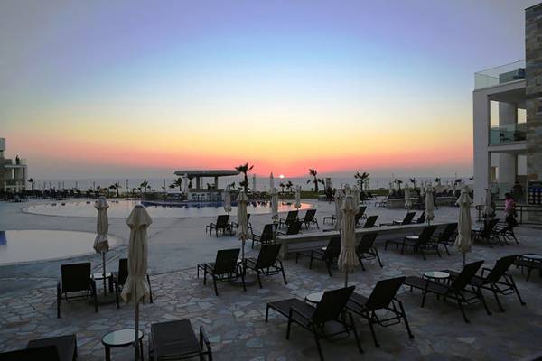 Sonnenuntergang am Poolbereich des Amphora Hotel & Suites mit Loungestühlen und Sonnenschirmen.