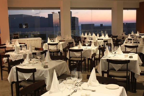 Innenansicht des Restaurants im Amphora Hotel & Suites mit gedeckten Tischen und Blick auf die Stadt.