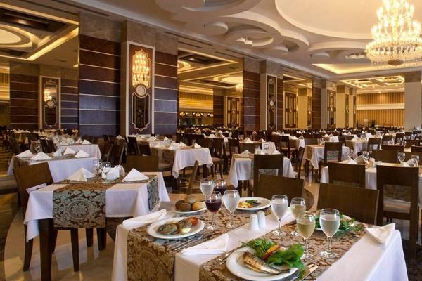 Restaurant des Oz Hotels Side Premium mit eleganten Tischen und Stühlen, einer großen Tafel und einer Kristallkronleuchter.
