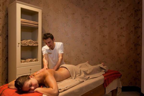 Massagebehandlung im Oz Hotels Side Premium mit einem Mann, der eine Frau auf einer Massageliege massiert.