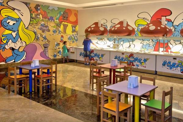 Kinderrestaurant mit smurfs thematischen Wandgemälden und Tischen und Stühlen.