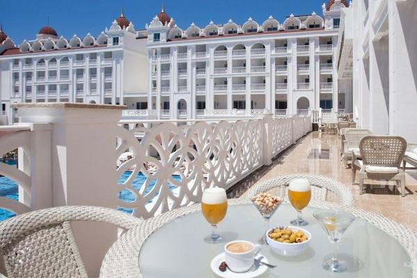Blick auf die Terrasse des Oz Hotels Side Premium mit einem Tisch und Getränken vor einem Swimmingpool.