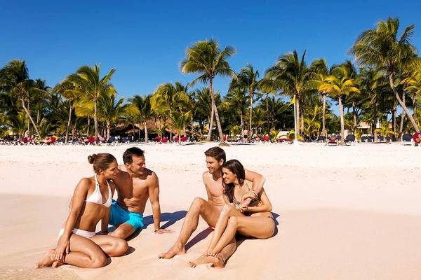 Vier Personen, zwei Paare, sitzen am Strand im Barcelo Maya Grand Resort.