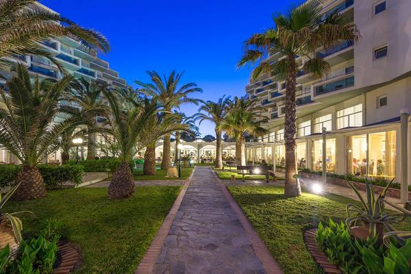 Apollo Beach Hotel Eingang mit Palmen und Gehweg bei Nacht