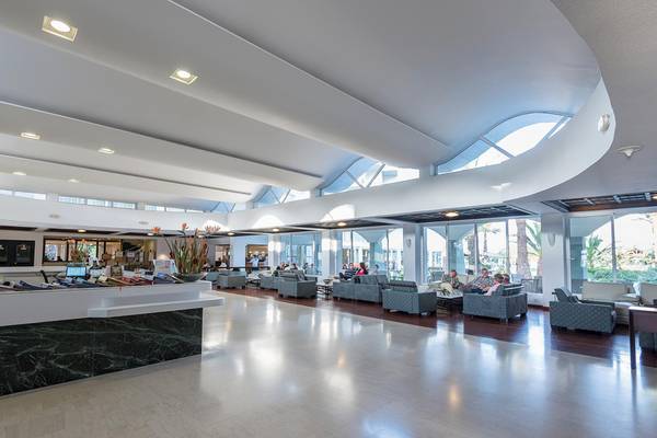 Lobby im Apollo Beach Hotel mit modernen Möbeln, hohen Decken und großen Fenstern.