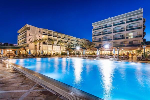 Außenpool des Apollo Beach Hotels bei Nacht mit Beleuchtung und Gebäude im Hintergrund.