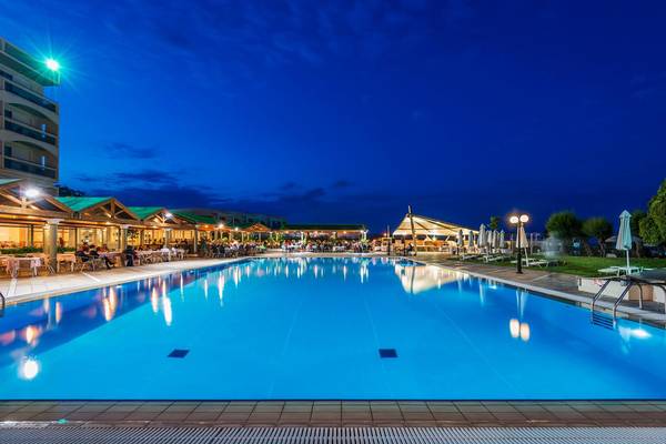 Der Außenpool des Apollo Beach Hotels bei Nacht mit Gästen und Beleuchtung.