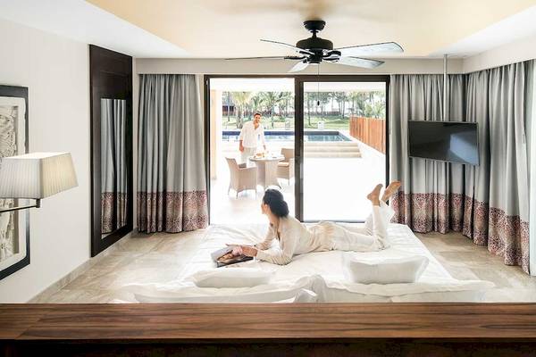 Schlafzimmer im Barcelo Maya Grand Resort mit Blick auf den Pool, zwei Personen entspannen sich.