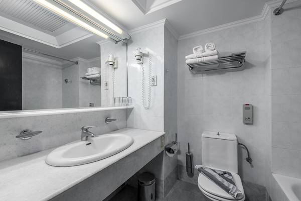 Badezimmer im Apollo Beach Hotel mit Waschbecken, Spiegel, Toilette und Handtüchern.