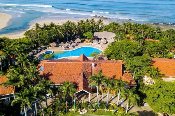 Luftaufnahme des Occidental Tamarindo Resorts mit Swimmingpool, Gebäuden und Palmen.