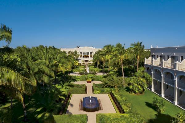 Aussenansicht des Dreams Tulum Resort & Spa mit einem großen Garten, Brunnen und Gebäuden.