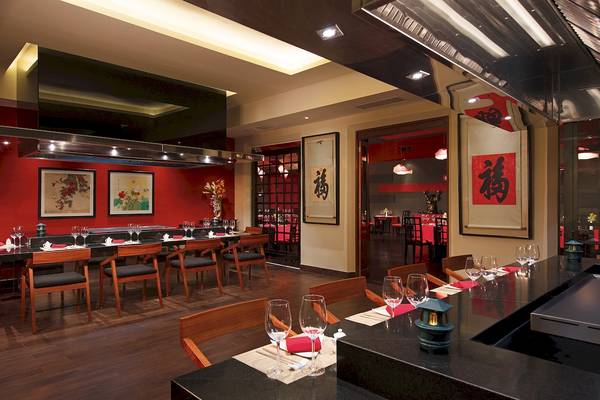 Innenansicht des Restaurants mit roten Wänden und Holztischen, dekoriert mit chinesischen Schriftzeichen.