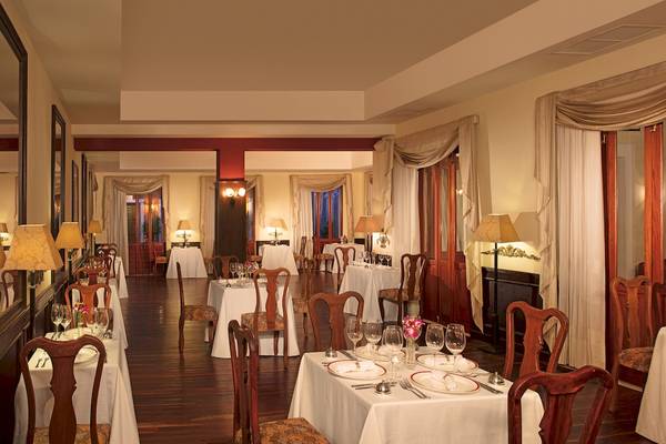 Innenbereich des Restaurants im Dreams Tulum Resort & Spa mit gedeckten Tischen und Stühlen.