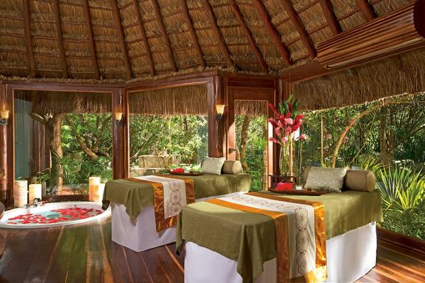 Spa-Behandlungsraum im Dreams Tulum Resort & Spa mit zwei Massagetischen und einem Whirlpool, umgeben von tropischer Vegetation.