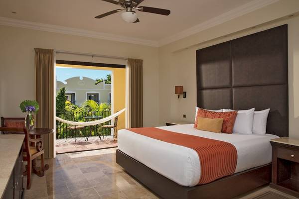 Suite mit Balkon im Dreams Tulum Resort & Spa mit Blick auf einen Außenbereich mit Tisch, Stühlen und Hängematte.