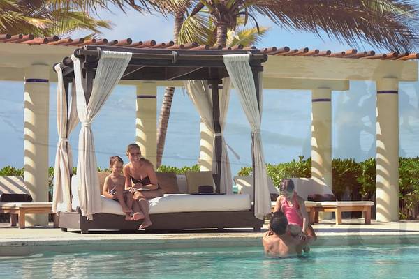Familie sitzt in einem Pool-Lounge-Bereich im Dreams Tulum Resort & Spa