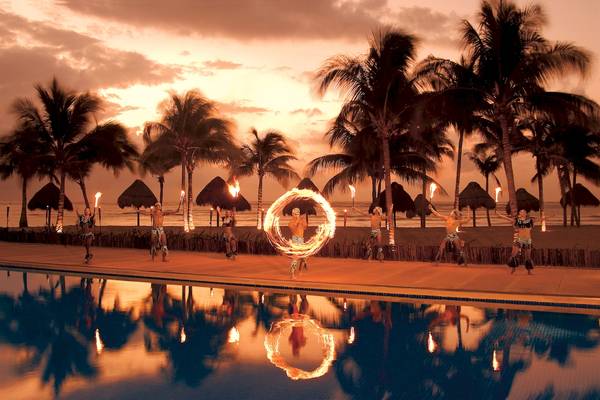 Ein Tanzensemble tanzt bei Sonnenuntergang am Pool des Dreams Tulum Resort & Spa.