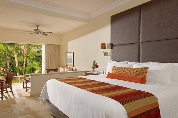 Luxuriöses Zimmer im Dreams Tulum Resort & Spa mit Blick auf Palmen und Außenbereich.