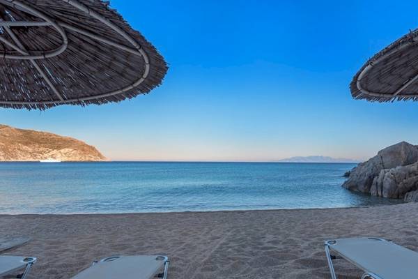 Strand mit Sonnenliegen, Sonnenschirmen und Blick auf das Meer und Felsen