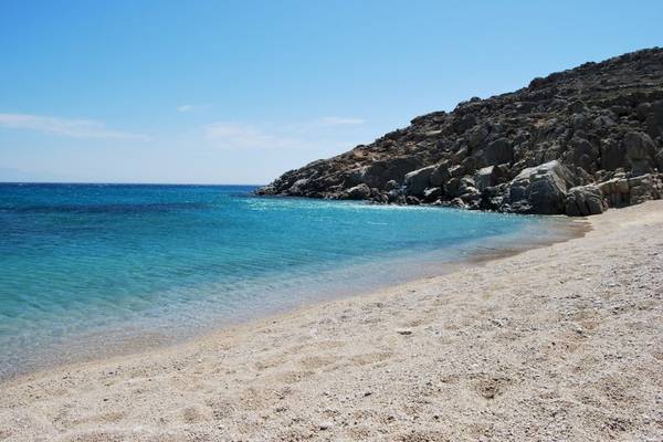 Strand mit felsigem Ufer und blauem Wasser unter einem blauen Himmel