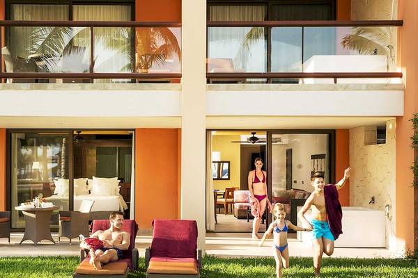 Familie genießt den Außenbereich des Barcelo Maya Grand Resort mit Balkon, Liegestühlen und Spielplatz