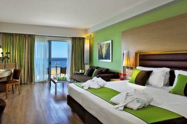 Minoa Palace Resort & Spa Hotelzimmer mit Meerblick, Bett, Sofa und Schreibtisch.