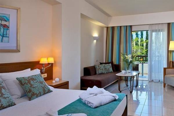 Minoa Palace Resort & Spa Hotelzimmer mit Bett, Couch, Tisch, Fernseher und Balkon