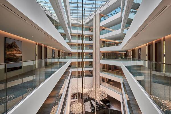 Innenansicht des Mysk Al Mouj Hotels mit Atrium, mehreren Ebenen und großen Glasfenstern.