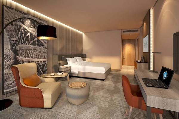 Innenansicht eines Hotelzimmers von Mysk Al Mouj mit Bett, Schreibtisch, Stühlen und Lampe.