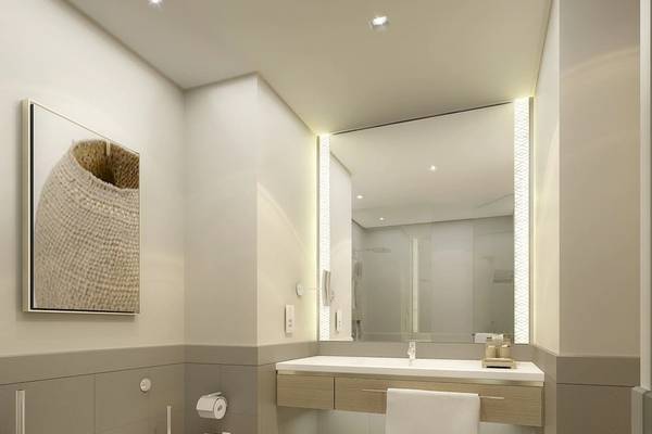Modernes Badezimmer im Mysk Al Mouj Hotel mit weißer Toilette, Spiegel und Handtüchern.