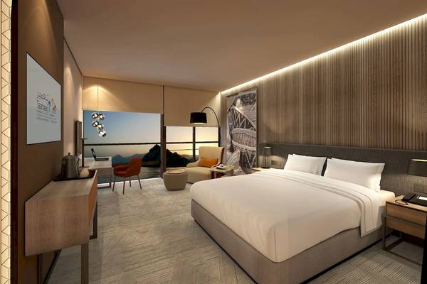Innenansicht eines eleganten Hotelzimmers im Mysk Al Mouj mit großem Bett, Aussichtsfenster und modernen Möbeln.