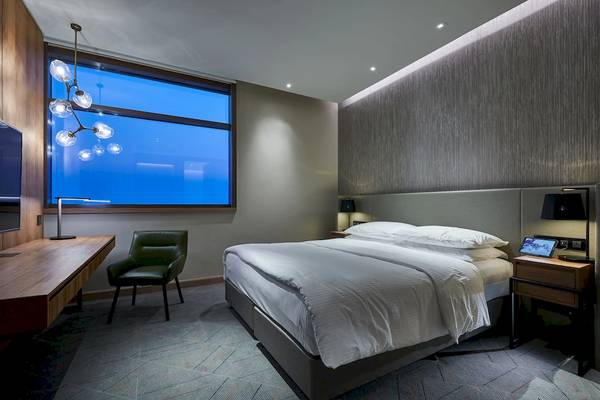 Hotelzimmer im Mysk Al Mouj mit großem Fenster, Bett, Schreibtisch und Lampe