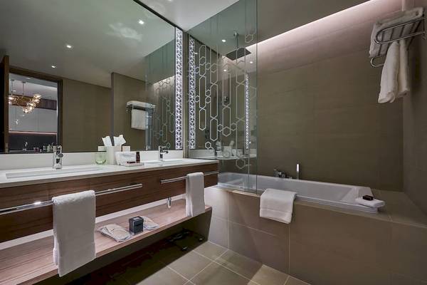 Modernes Badezimmer im Mysk Al Mouj Hotel mit Doppelwaschbecken, Badewanne und Dusche.