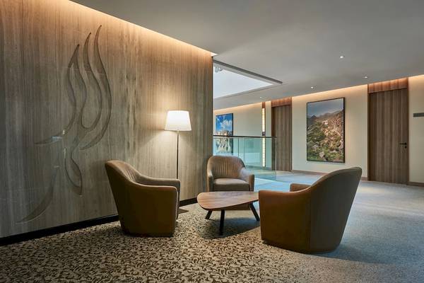 Lobby-Lounge-Bereich im Mysk Al Mouj Hotel mit Möbeln, Lampen und Kunstwerken.