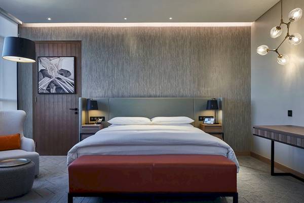 Schlafzimmer im Mysk Al Mouj Hotel mit einem großen Bett, roten Kissen und Holzmöbeln.