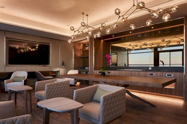 Loungebereich im Mysk Al Mouj Hotel mit Holzmöbeln und großen Fenstern.